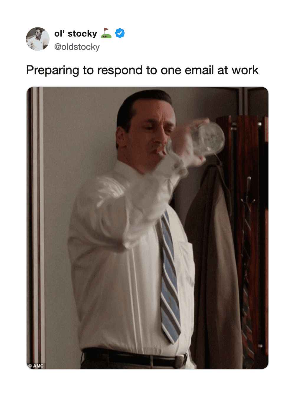 Man in white shirt drinking from a glass, preparing to respond to an email at work.