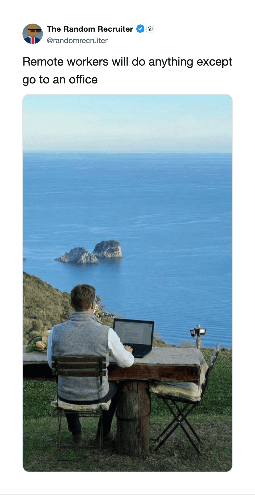 Remote worker with laptop overlooking ocean and islands, working outdoors.