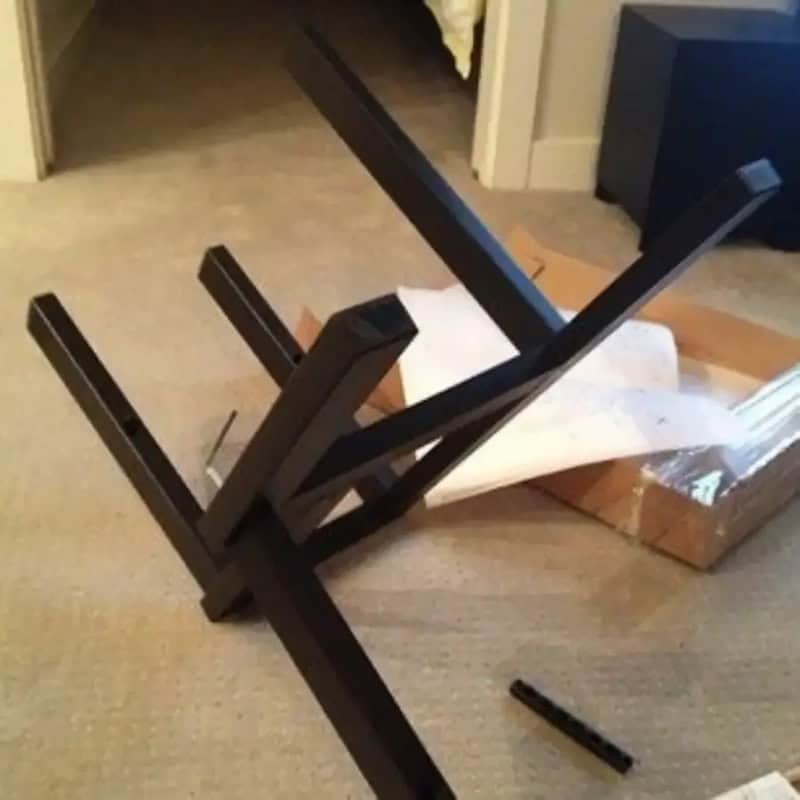 Upside-down black table with broken leg on a beige carpet.