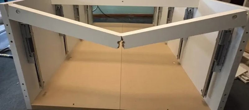Partially assembled furniture with a misaligned top panel and missing screws.