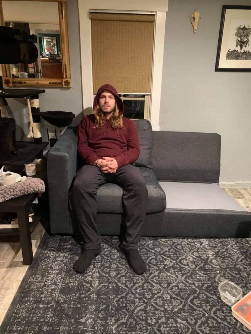 Man sitting on a sofa in a living room with furniture assembly fails.