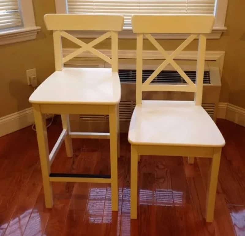 Two yellow chairs with mismatched seat heights in a room with hardwood floor.