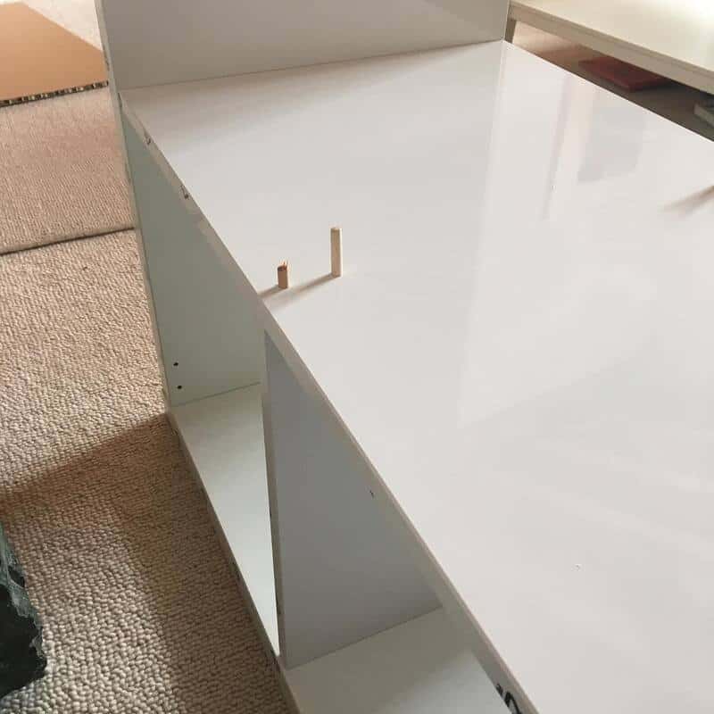 Partially assembled white furniture with missing parts and tools.