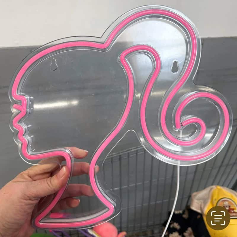 Pink neon sign in the shape of a woman's profile with a swirl hair design.