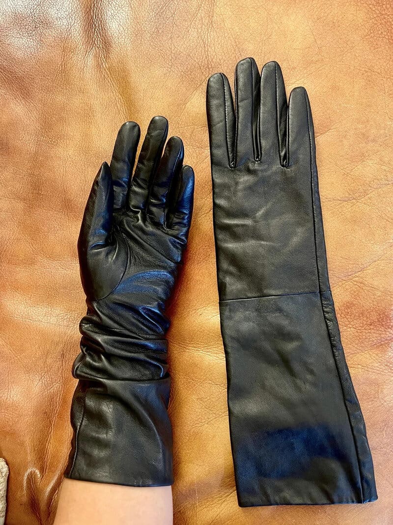 Pair of black leather gloves on a brown surface.