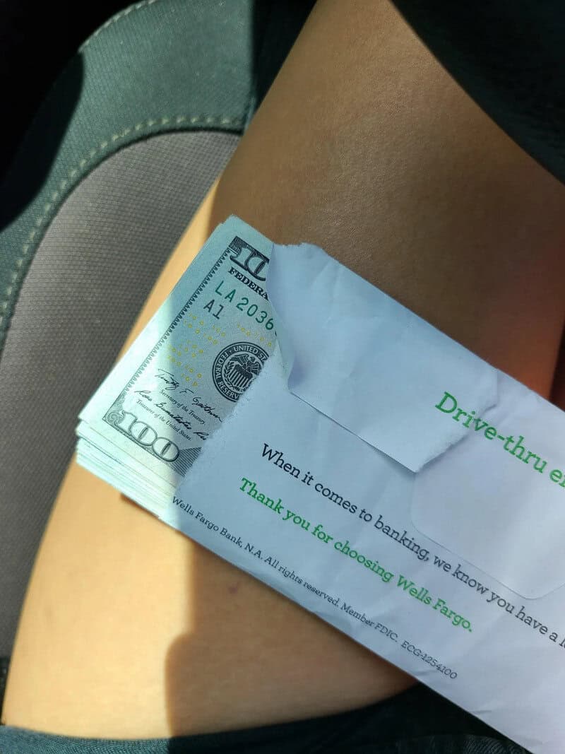 A $100 bill tucked into a paper bag with a drive-thru receipt, on a person's leg.