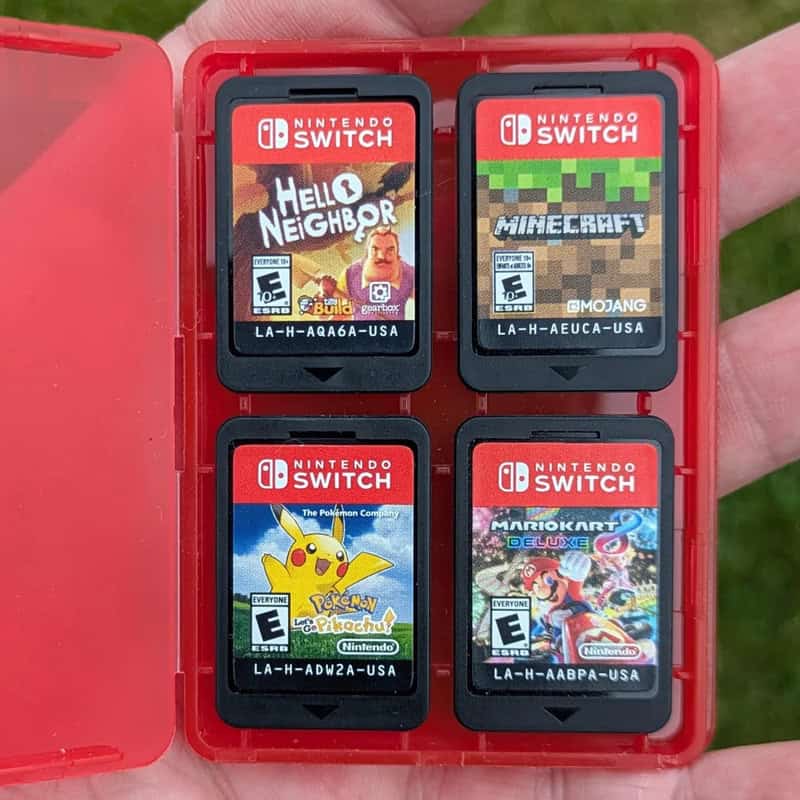 Four Nintendo Switch game cartridges in a red case, including Hello Neighbor, Minecraft, Pokémon Pik.