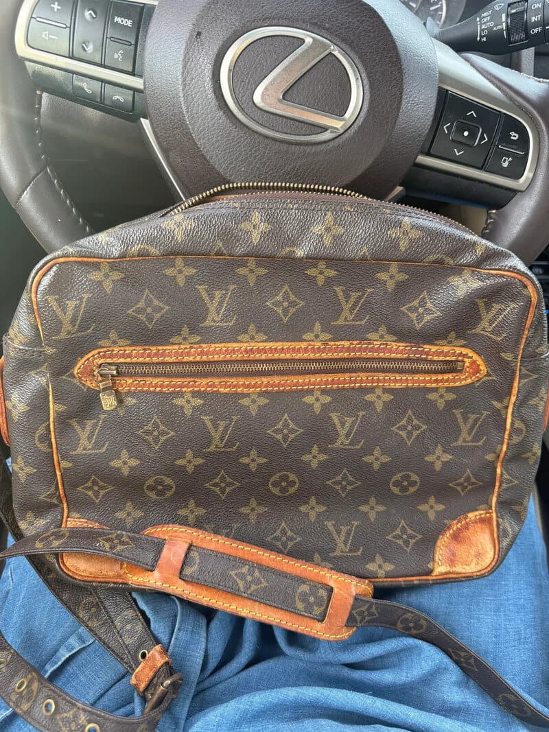 Louis Vuitton bag on lap in a Lexus car interior, steering wheel visible.