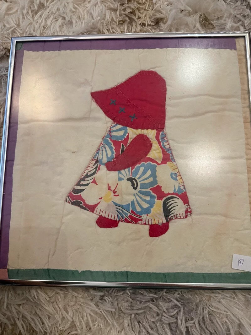 Child's fabric doll with red hood, floral dress, and red shoes, in a box.