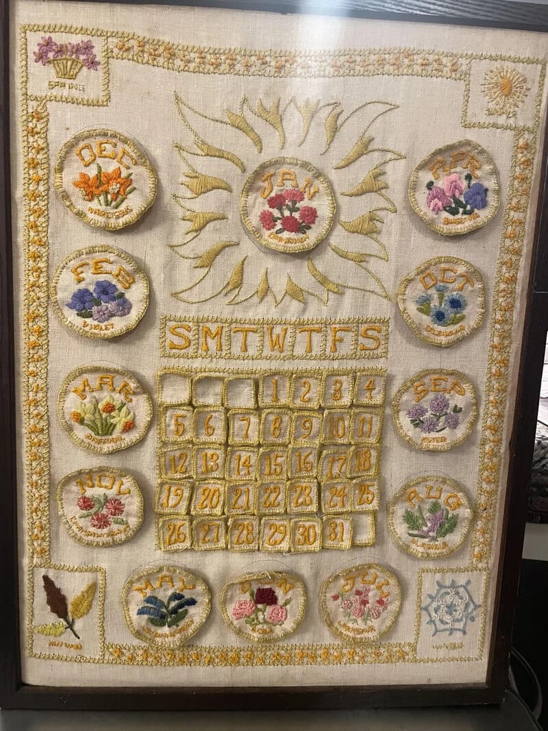 Decorative calendar with flowers and sun motif, labeled with days and months.