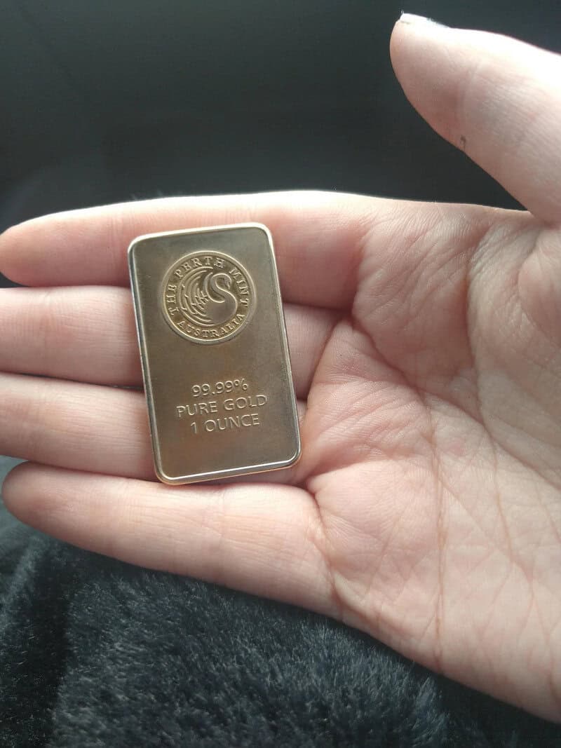 Small gold bar with '99.99% PURE GOLD 1 OUNCE' and a logo on it.
