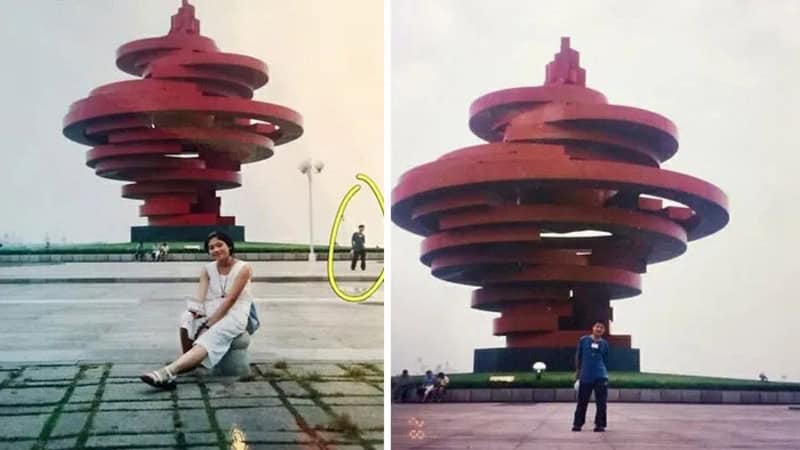 Person sitting on ground near a large red spiral sculpture, with another person standing nearby.