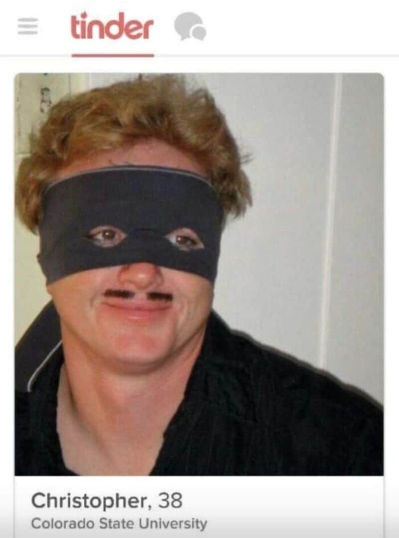 Man with a black mask over eyes, mustache, and curly hair on Tinder.