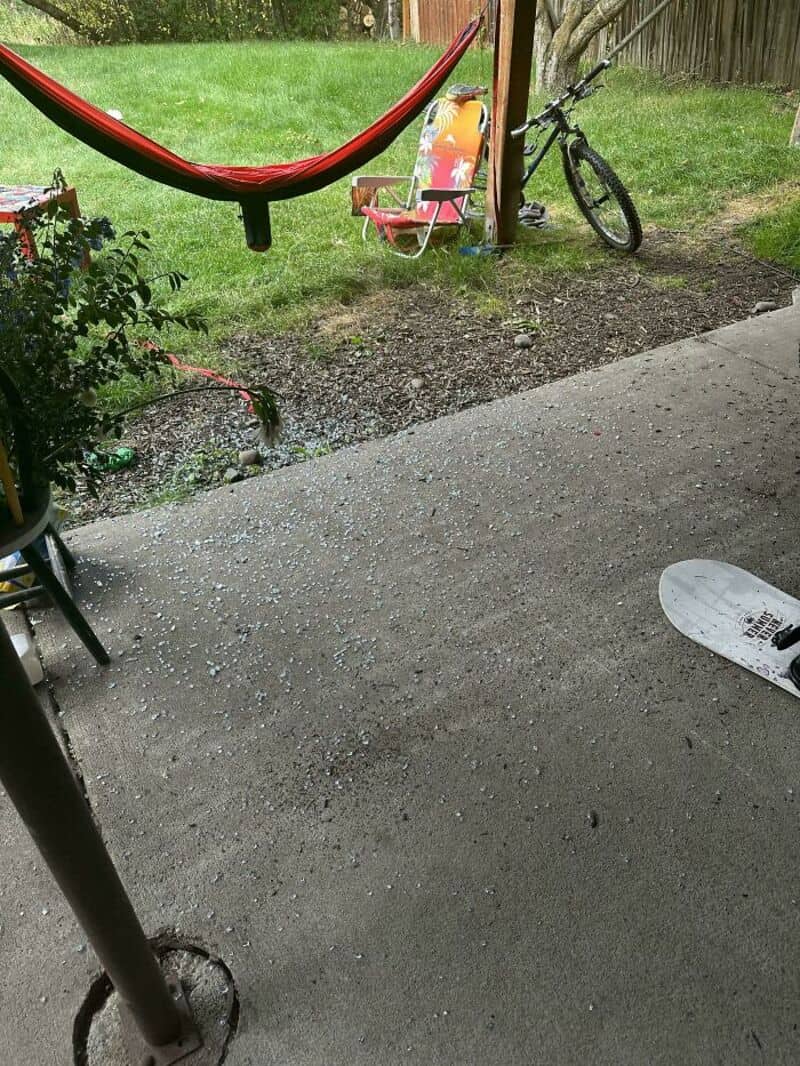 Backyard with hammock, bike, and lawn chair, viewed from a concrete patio.