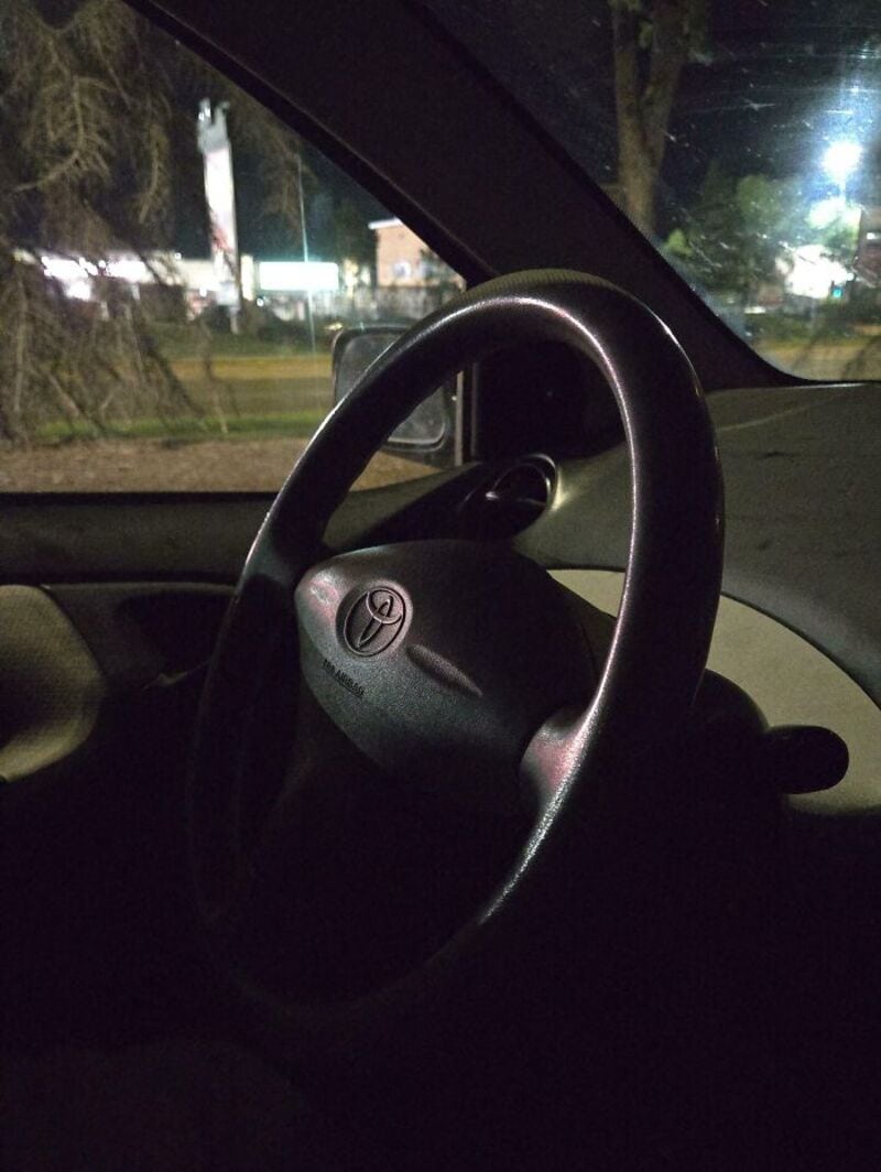 Car steering wheel with a logo, inside a vehicle at night.