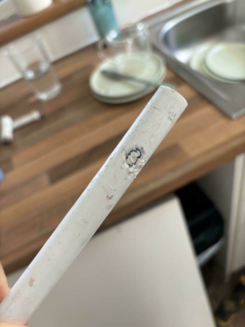 A white cigarette with a burn mark on it, held over a kitchen counter.