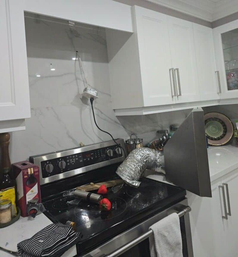 Kitchen with stove, cabinets, and a makeshift vent duct made from aluminum foil.