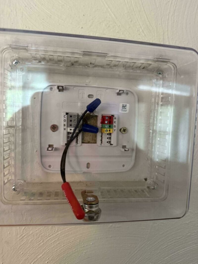 Electrical box with wires and fuses, cover removed, on a wall.