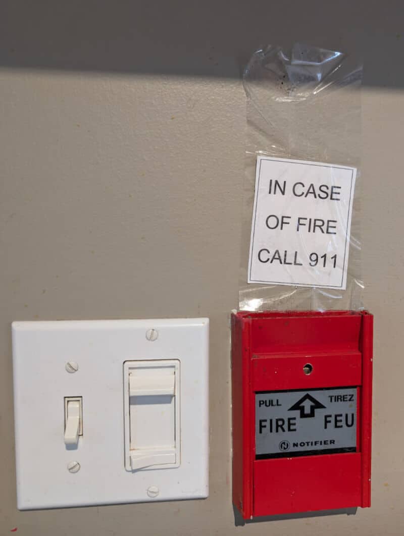 Fire alarm box and a note on the wall reading 'In case of fire call 911'.