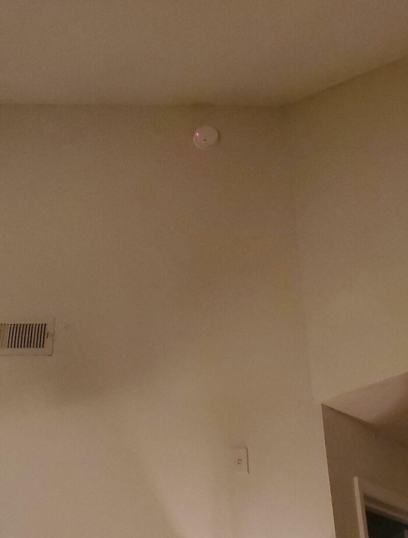 Smoke detector on ceiling, wall vent, and light switch in room.