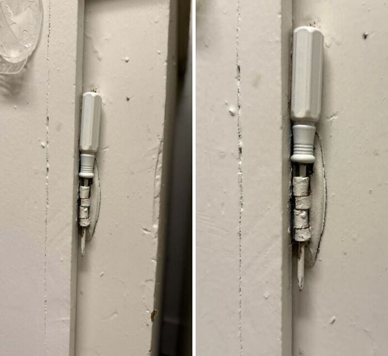 Broken door lock with makeshift repair using a screwdriver and tape.