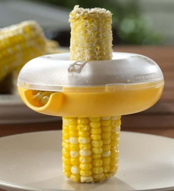Corn on the cob in a yellow holder with a clear lid, on a white plate.