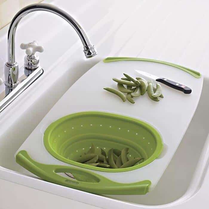 Green vegetable slicer with sliced vegetables on a white cutting board.