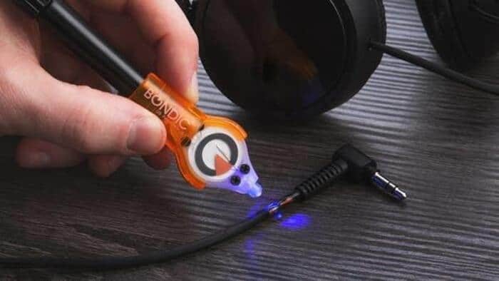 Person using a glue stick to attach a small LED light to a headphone cable.