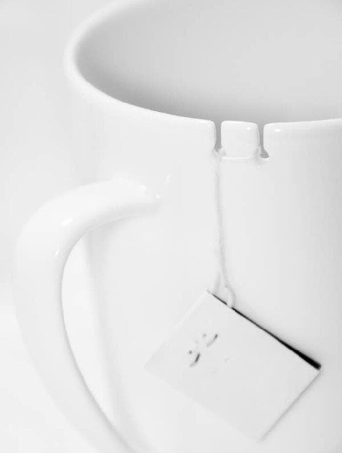 White mug with a tea bag hanging inside, on a white background.