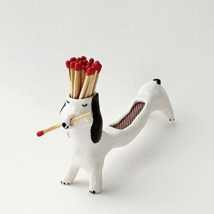 Dog-shaped matchstick holder with matches in its head and a tail that opens for storage.