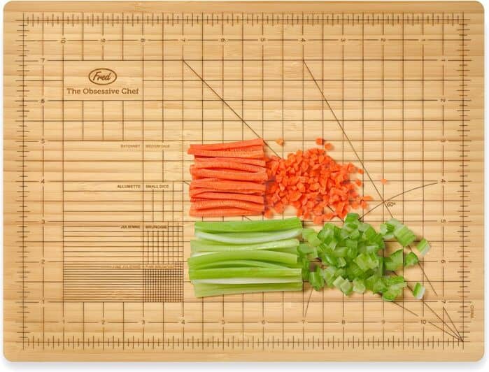 Chopped carrots, celery, and green onions on a wooden cutting board.