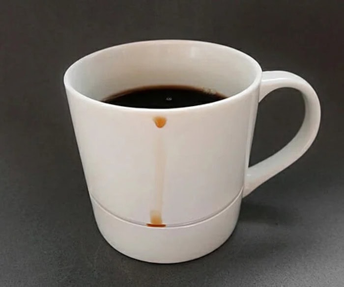 Coffee mug with coffee and a coffee stain on the side.