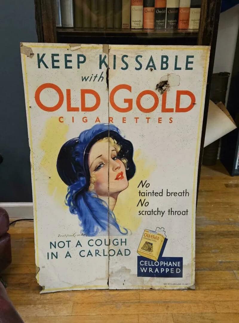 Vintage Old Gold Cigarettes sign with a woman and text about the product.
