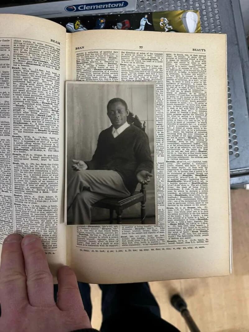 Black and white photo of a man sitting on a chair in a book page.