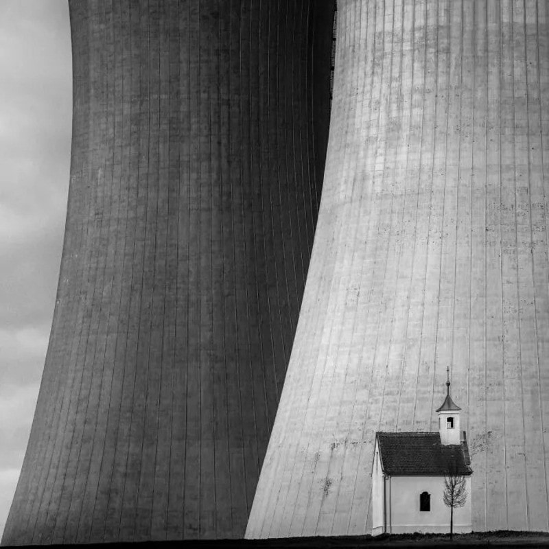 Black and white photo of a small church between two large cooling towers.