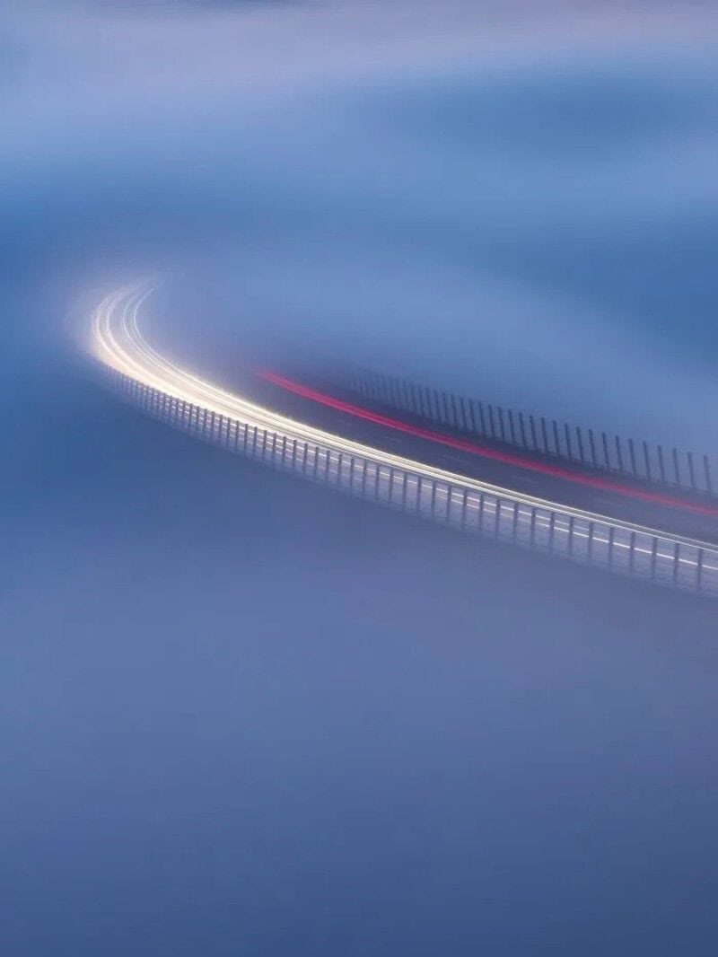 Abstract long exposure photo of a curved road with light trails in blue tones.