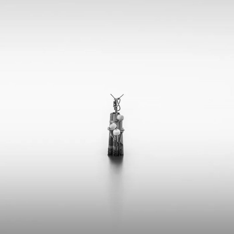Minimalist sculpture on a smooth surface with a plain background.