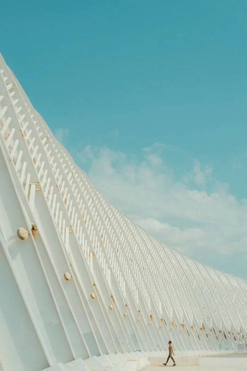 Modern architectural structure with white curved beams against a blue sky.