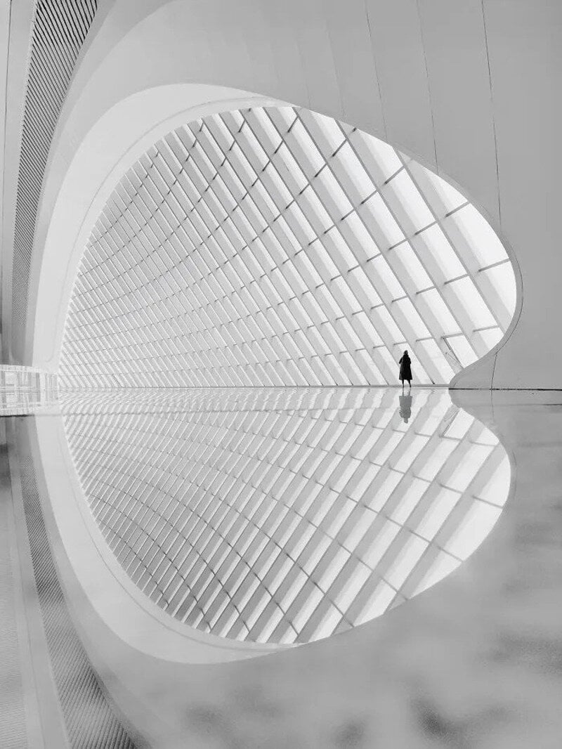 Modern architectural interior with large glass windows and a single person walking.