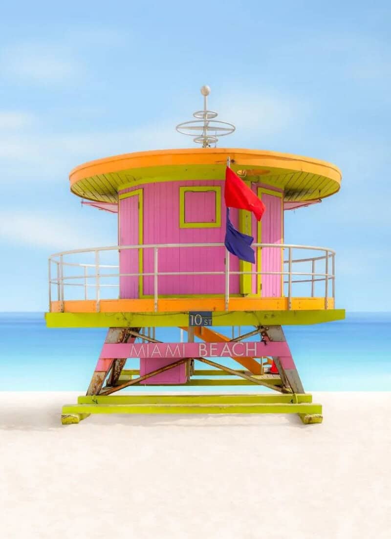Colorful lifeguard tower on Miami Beach with flags and ocean background.