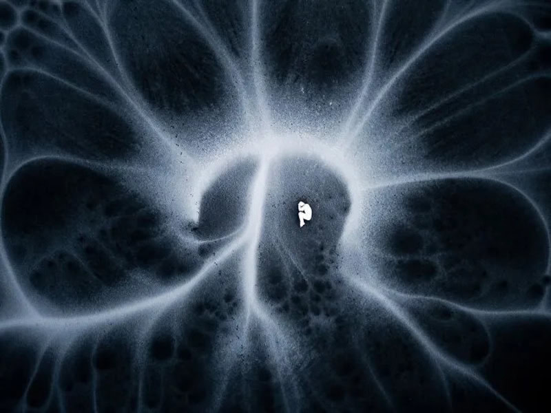 Abstract black and white image with swirling patterns and a central bright spot.