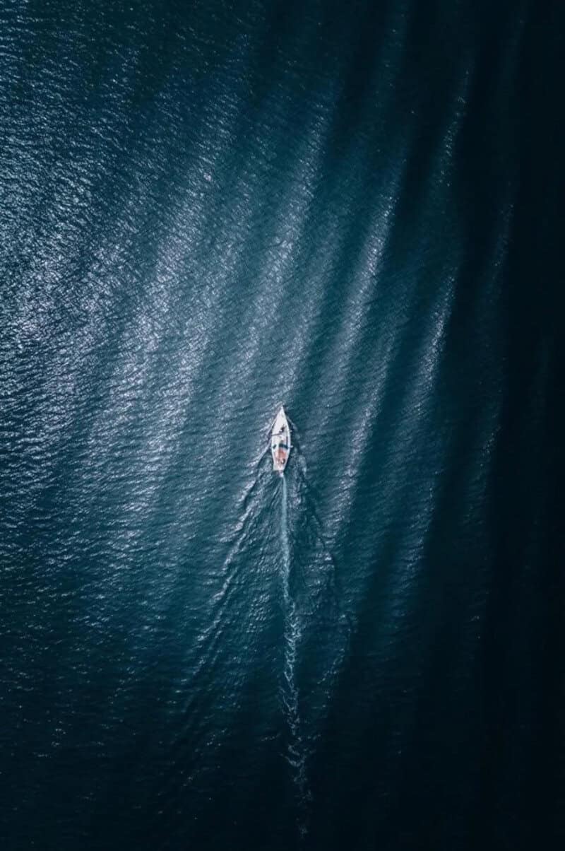 A boat sailing on calm water with ripples and reflections.