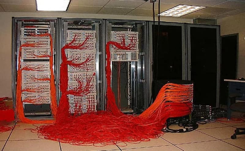 Server racks with tangled red network cables in a data center.