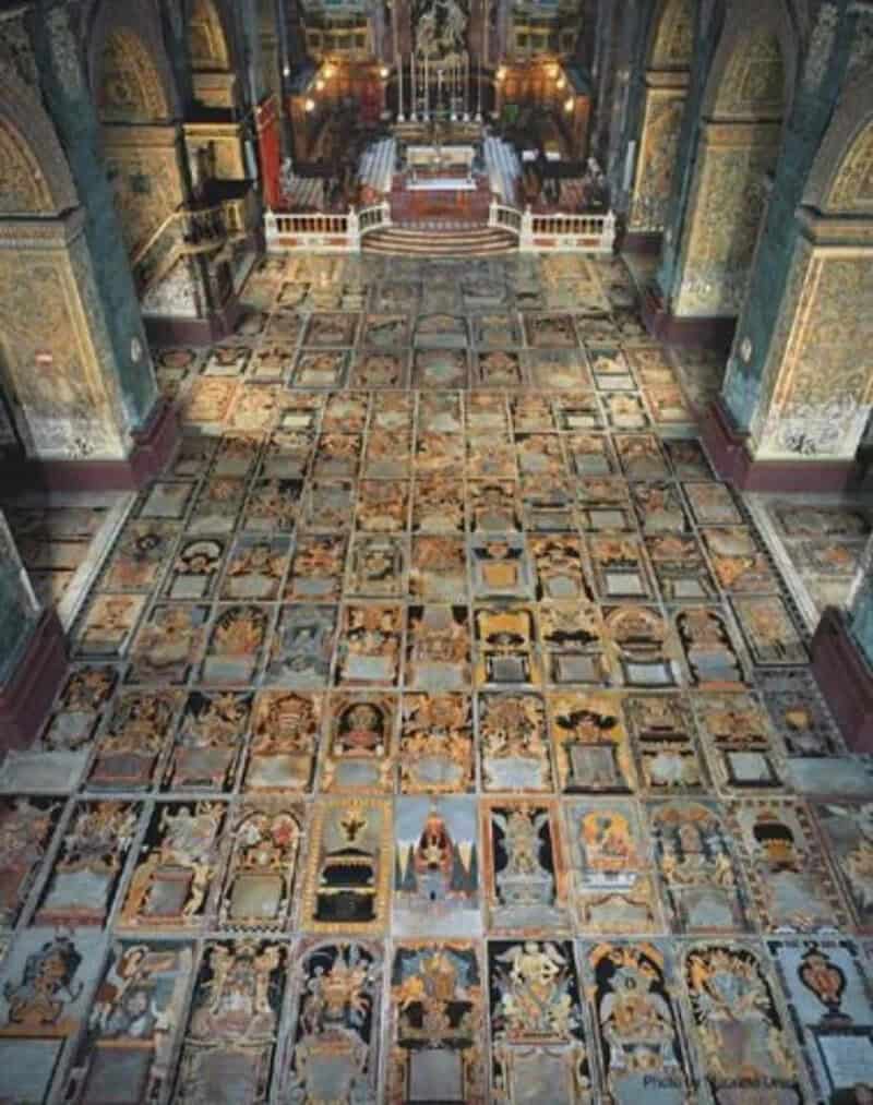Ornate church interior with a decorated tiled floor and high vaulted ceilings.