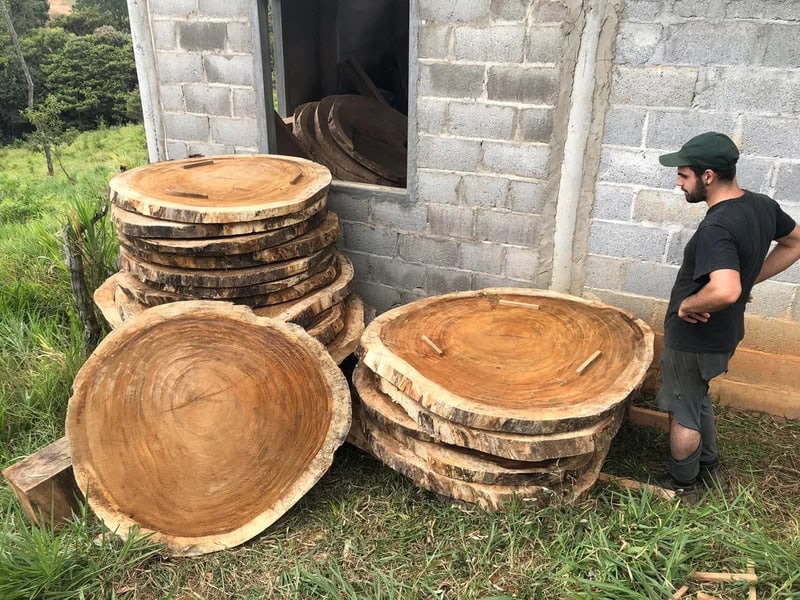 Man standing next to large wooden tree slices outside a building.