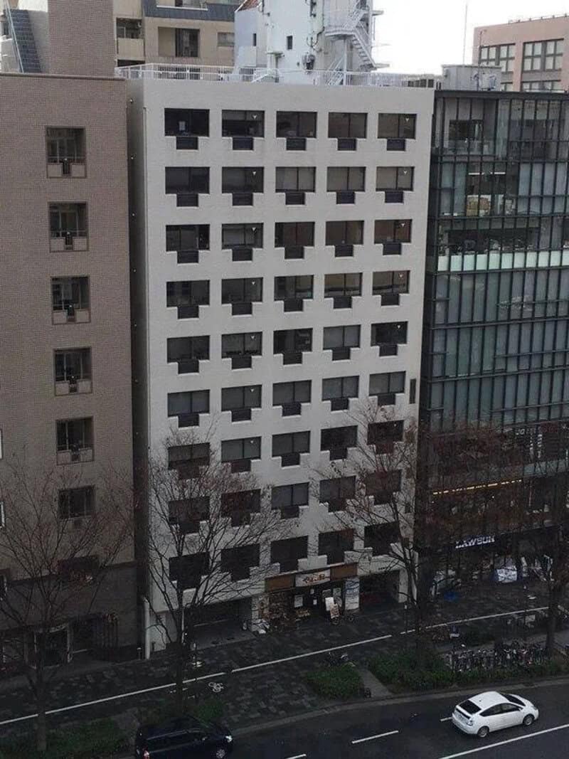 Tall white building with black window frames in an urban area.