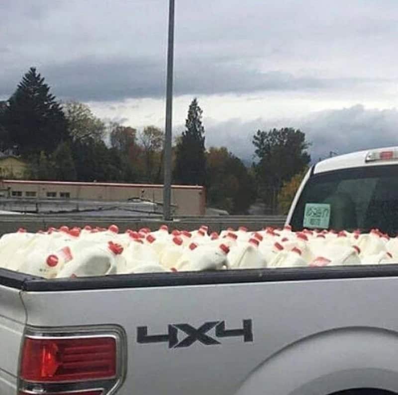 Pickup truck with milk jugs in the bed, under a cloudy sky.
