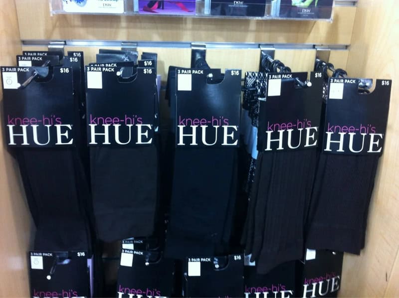 Black knee-high socks with pink and white text, displayed on a store shelf.