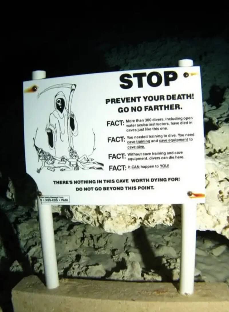 Warning sign about cave safety with a grim reaper illustration and safety facts.
