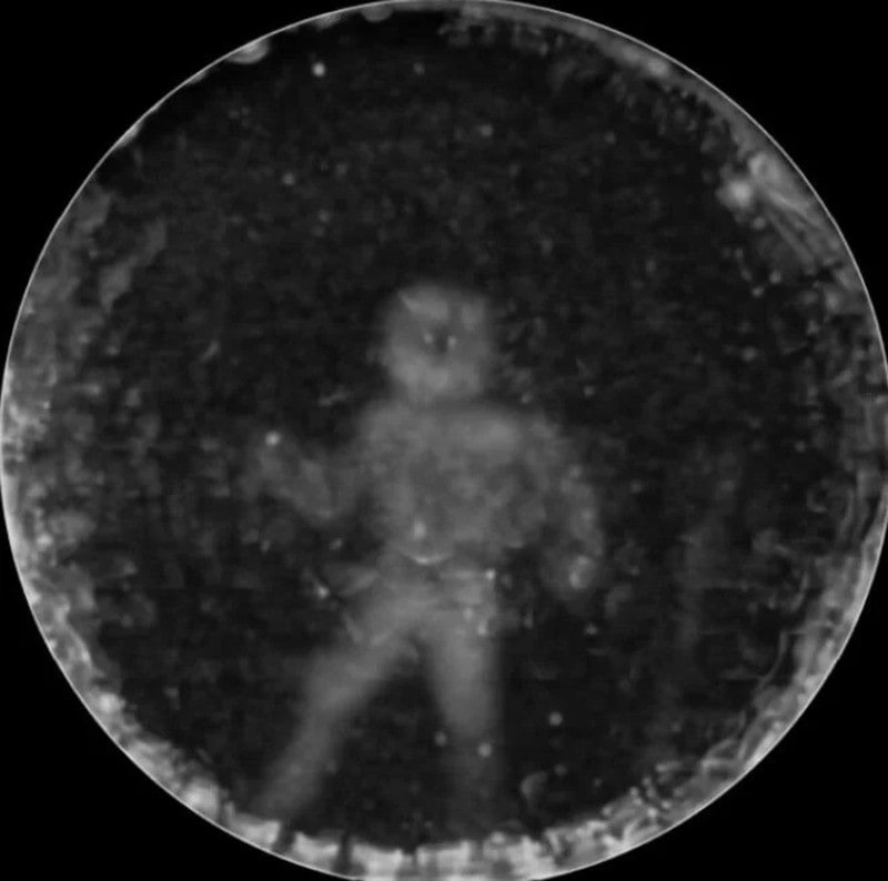 Child's face pressed against a glass ball with stars inside, in black and white.